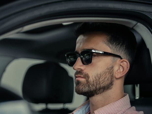 A man in sunglasses at the wheel of his car.