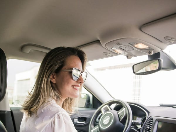 A woman smiling at the wheel of her car.